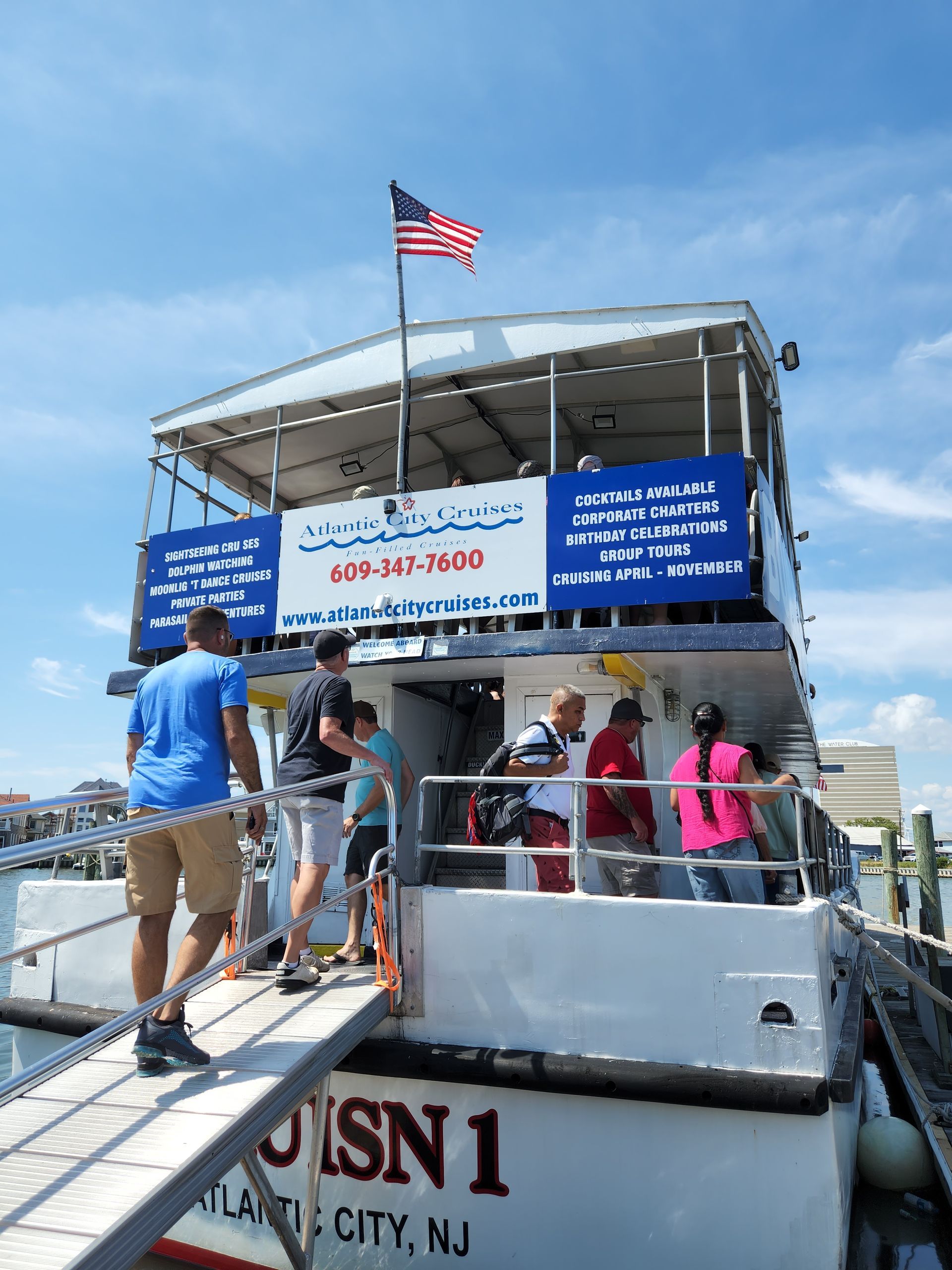 People boarding a boat in Atlantic City, NJ, under a blue sky, with an American flag flying.