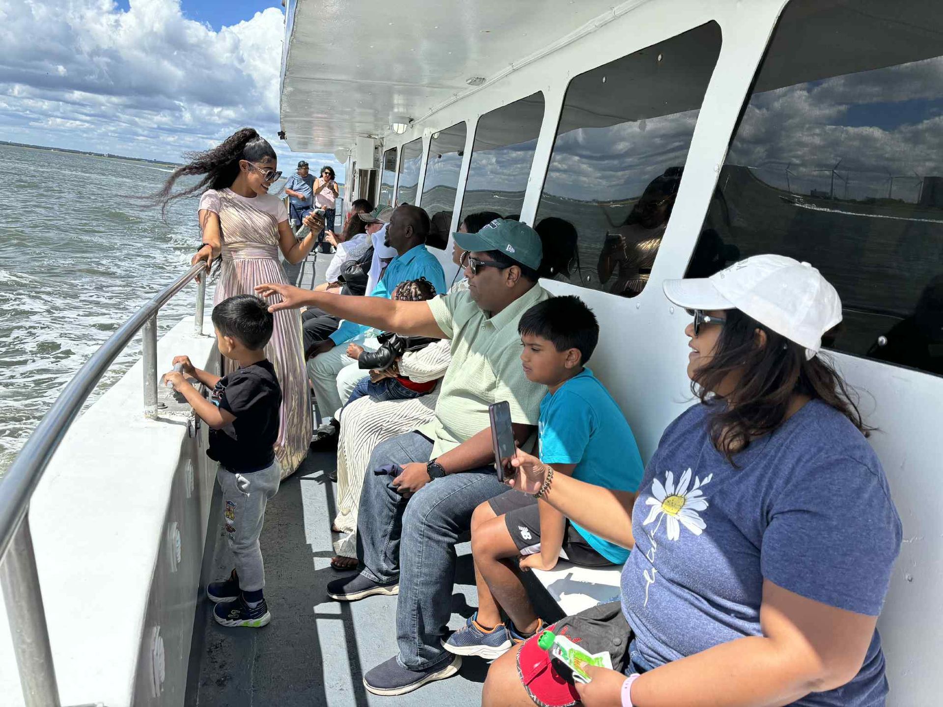 People on a boat looking out at the water; sunny day with some clouds.