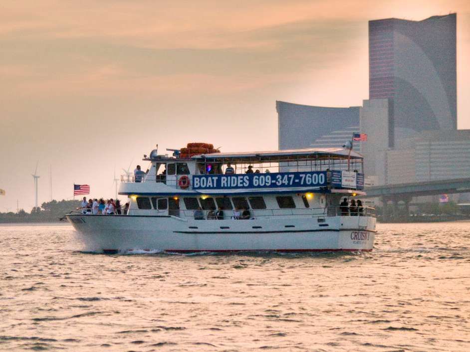 Boat on water with people on board, skyline in background.