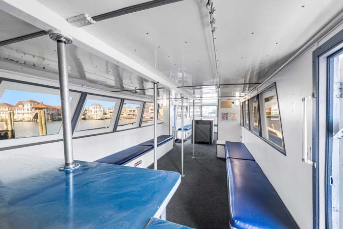 Interior of a boat with blue seats and windows showing a Venetian canal.