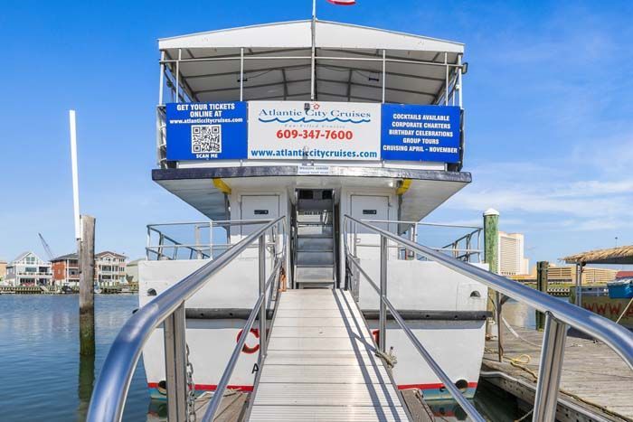 Back of a boat docked at a pier, with a ramp leading up. Sign: Atlantic City Cruises.