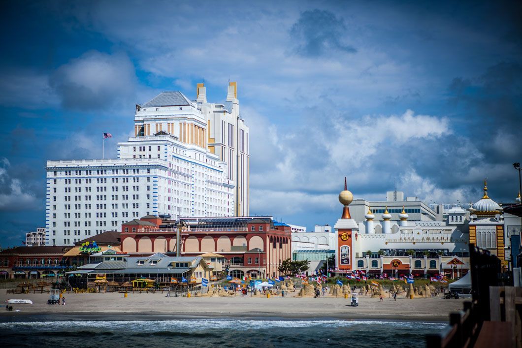 Beachfront buildings under a cloudy sky. A large, white hotel stands tall behind other buildings, near a pier.