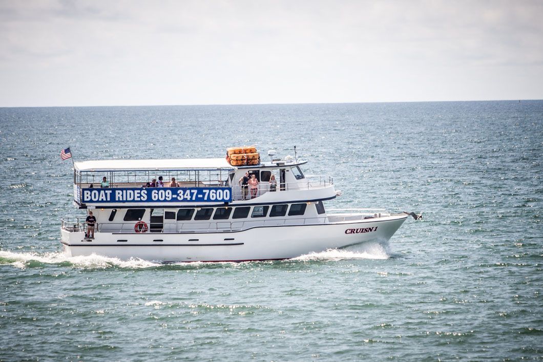 Boat with passengers, blue and white, on ocean, advertising boat rides.