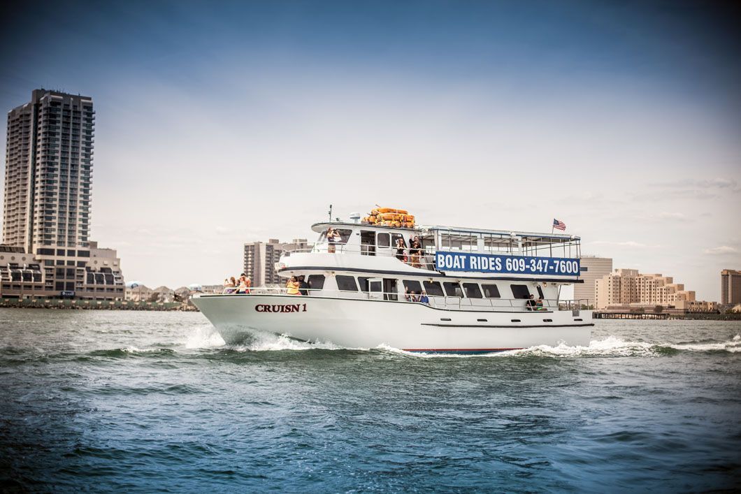 White tour boat cruising on water, skyscrapers in the background.