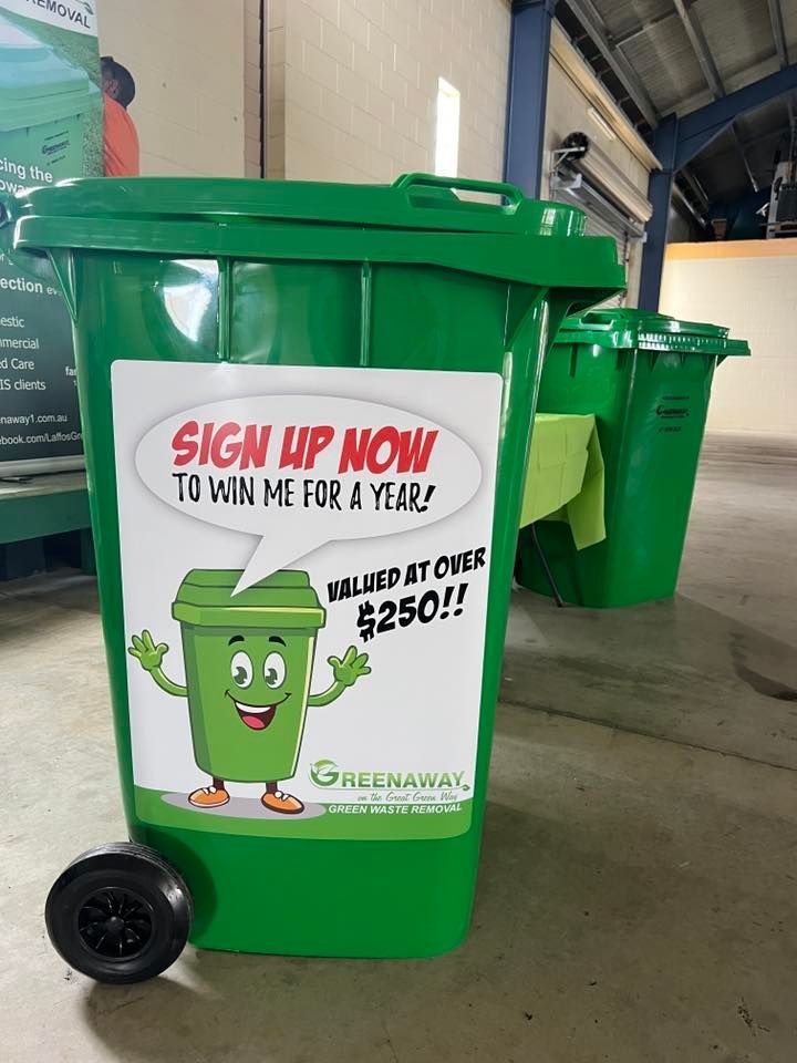 Green recycling bin with a sign that says