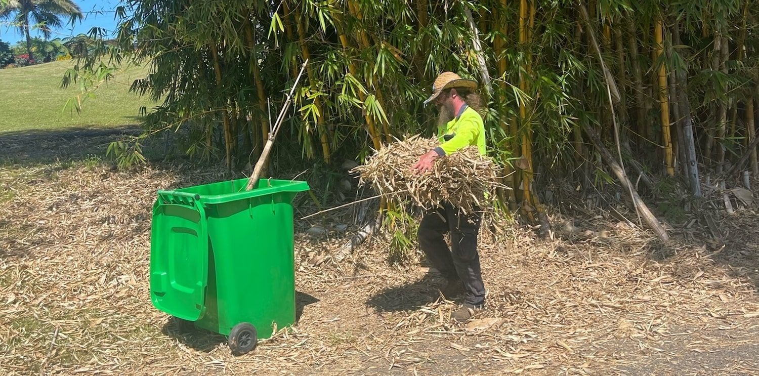 A Man is Standing Next to a Green Trash — Greenaway Green Waste Removal in O'Briens Hill, QLD