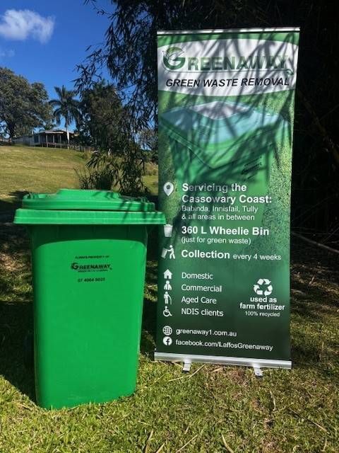 Green waste removal service advertisement. Green bin and banner on grass, sunny outdoor setting.— Greenaway Green Waste Removal in Mission Beach, QLD