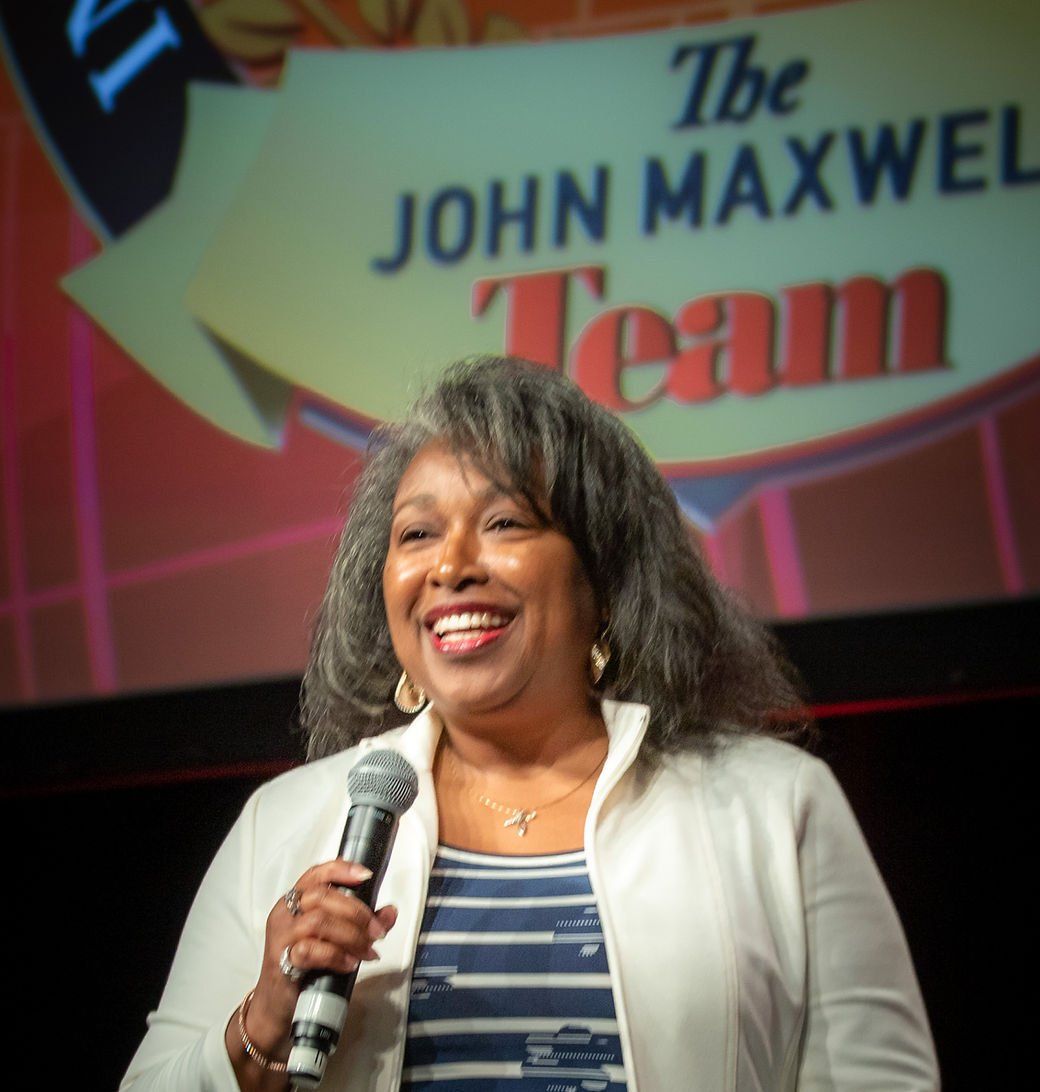 Woman, smiling, holds a microphone. She speaks at