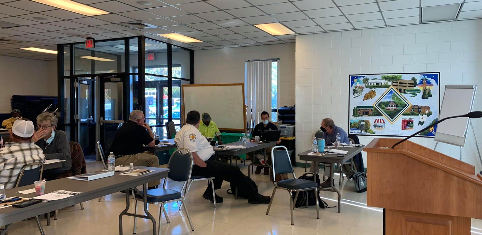 People seated at tables, possibly in a meeting or presentation setting.