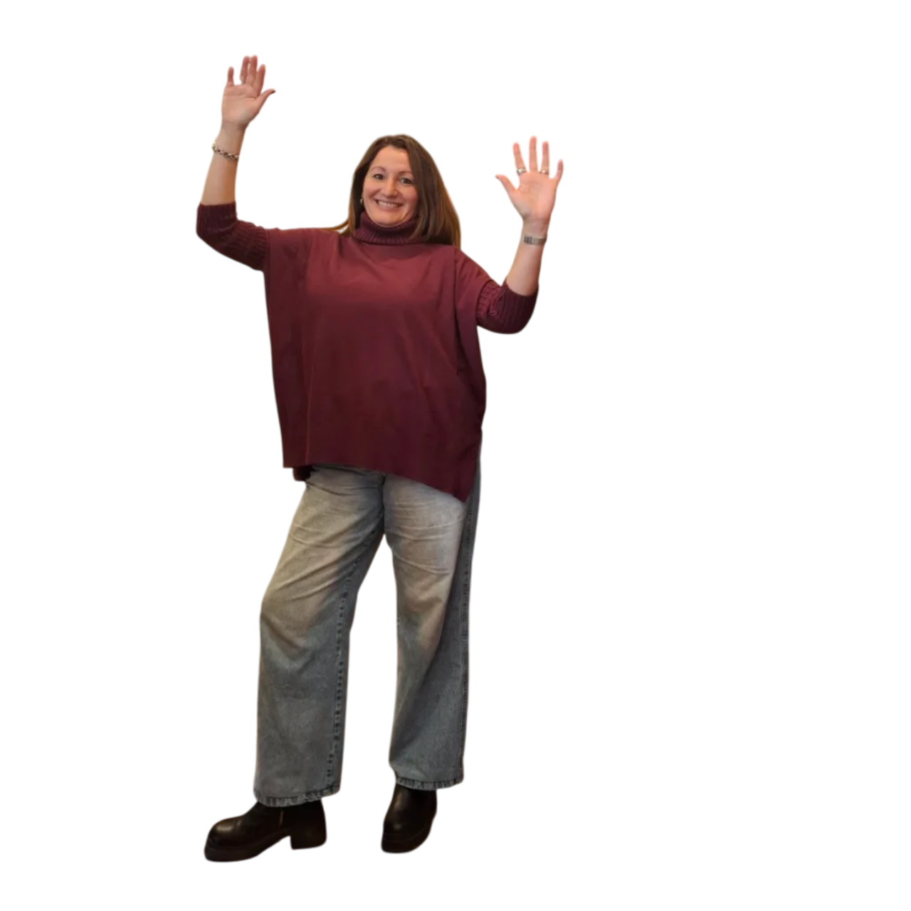 Mujer con las manos levantadas, sonriendo, vestida con un suéter granate y pantalones vaqueros.