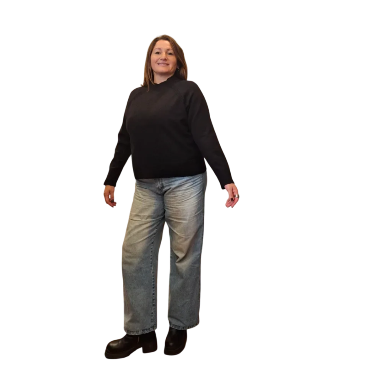Mujer con suéter negro y jeans de pie con los brazos a los lados.