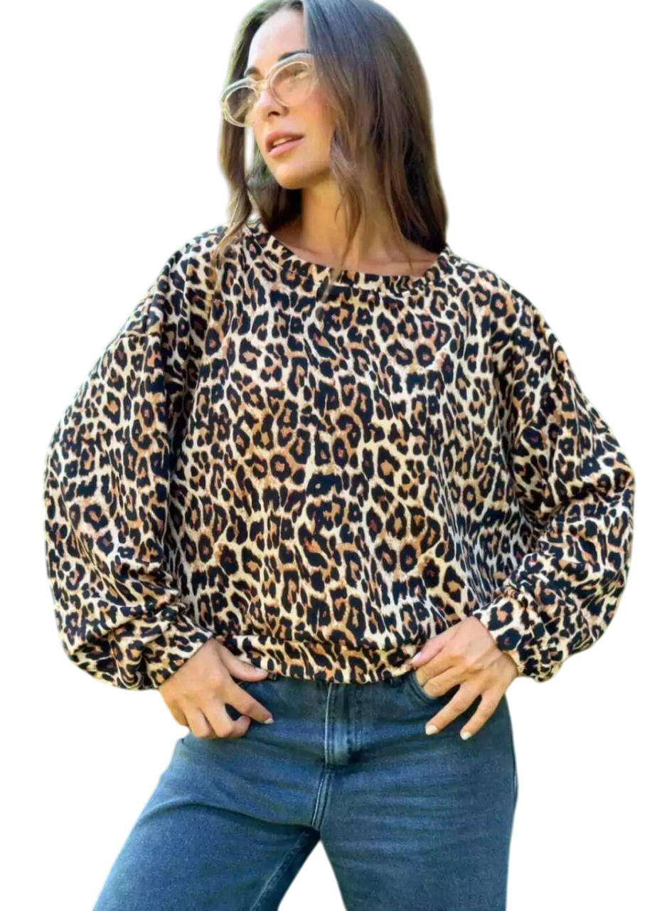 Mujer con sudadera de estampado de leopardo y vaqueros azules, de pie al aire libre.