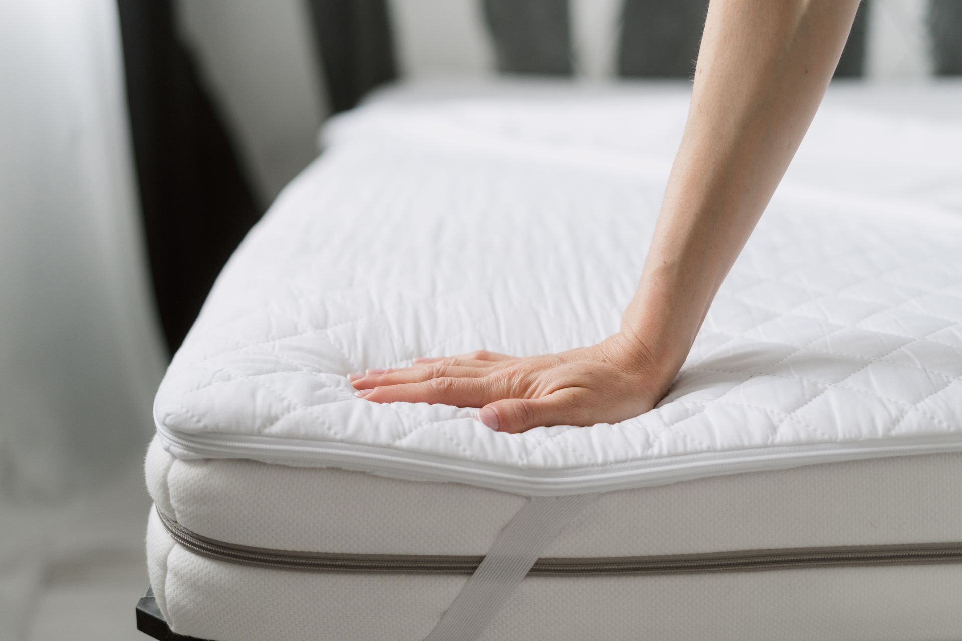 A close-up of a woman checking a mattress with a textile cover. A close-up of a woman checking a mattress with a textile cover.