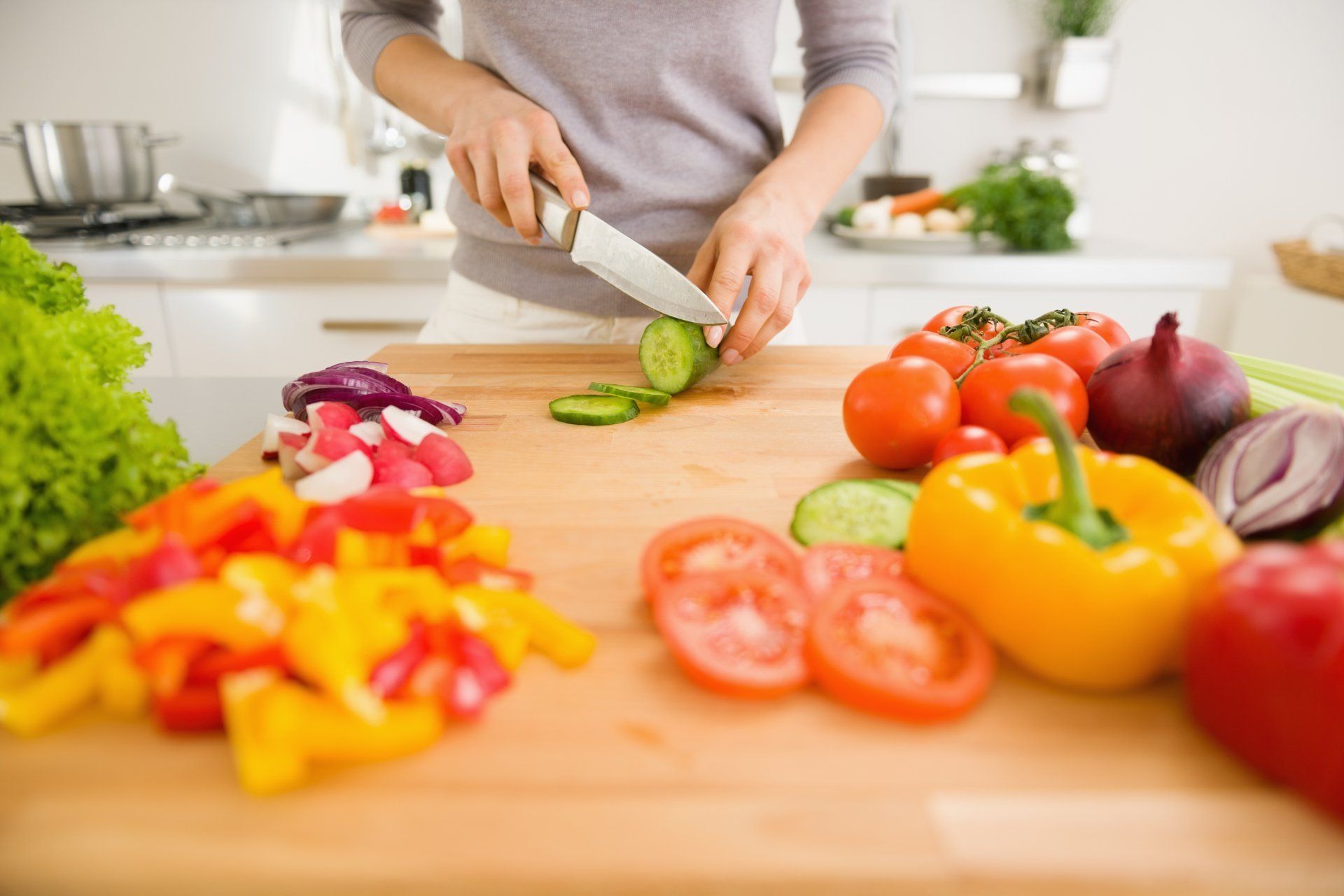 A person cutting vegetables in a kitchen.