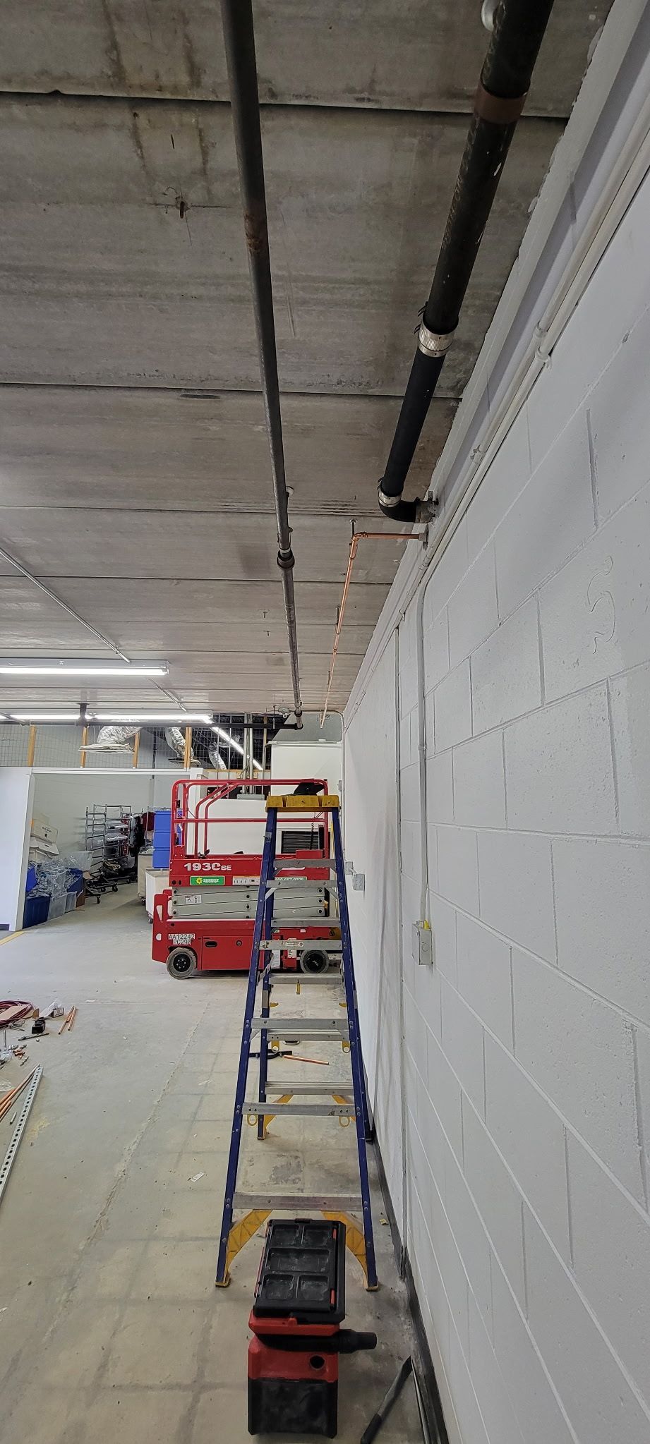 A row of ladders are lined up against a white wall in a room.