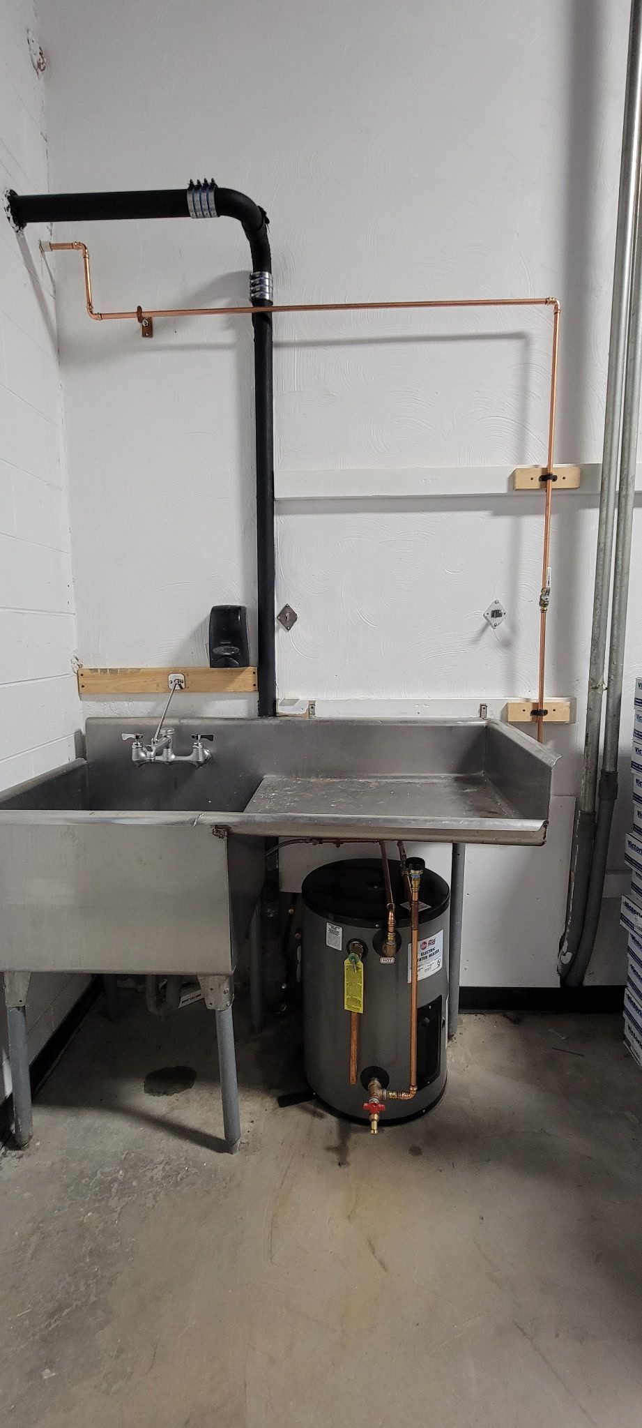 There is a sink and a water heater in the room.