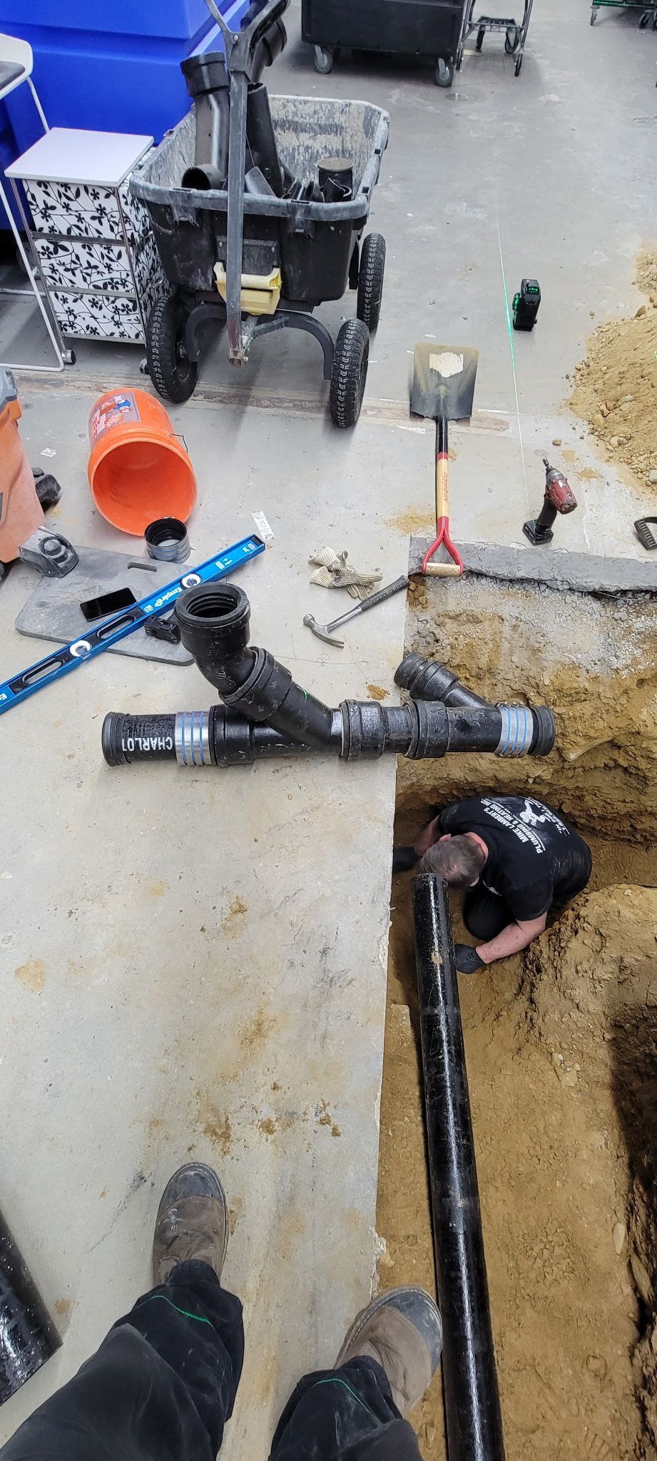A man is working on a pipe in a hole in the ground.