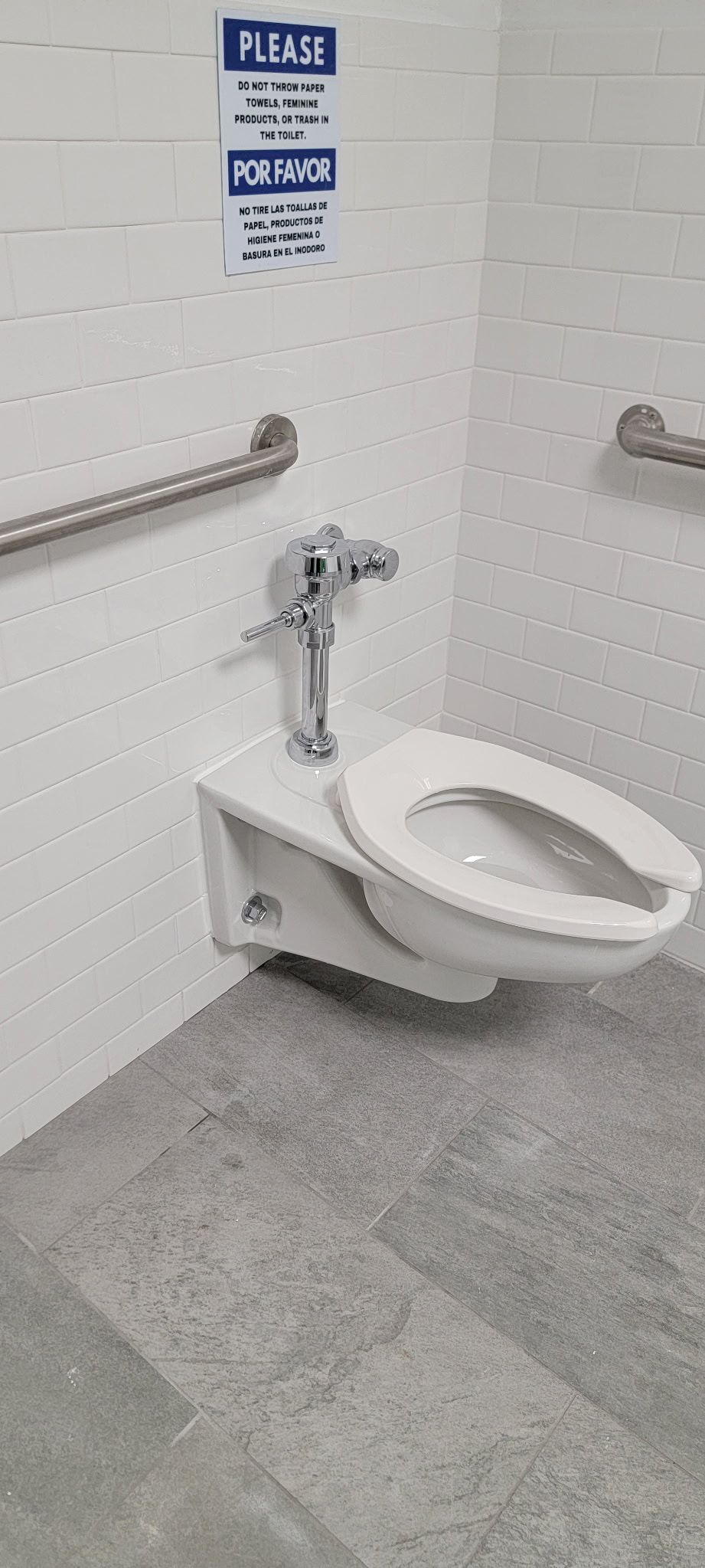 A toilet is mounted to the wall in a bathroom.