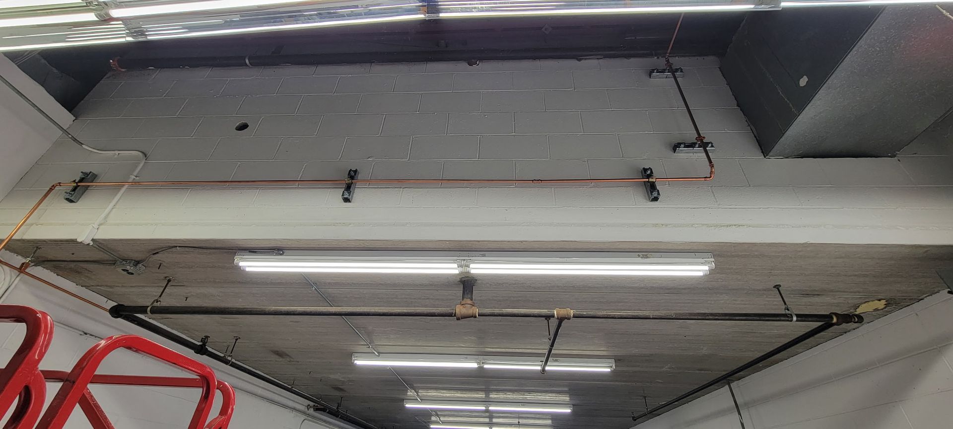 A ceiling with a lot of lights and pipes hanging from it.