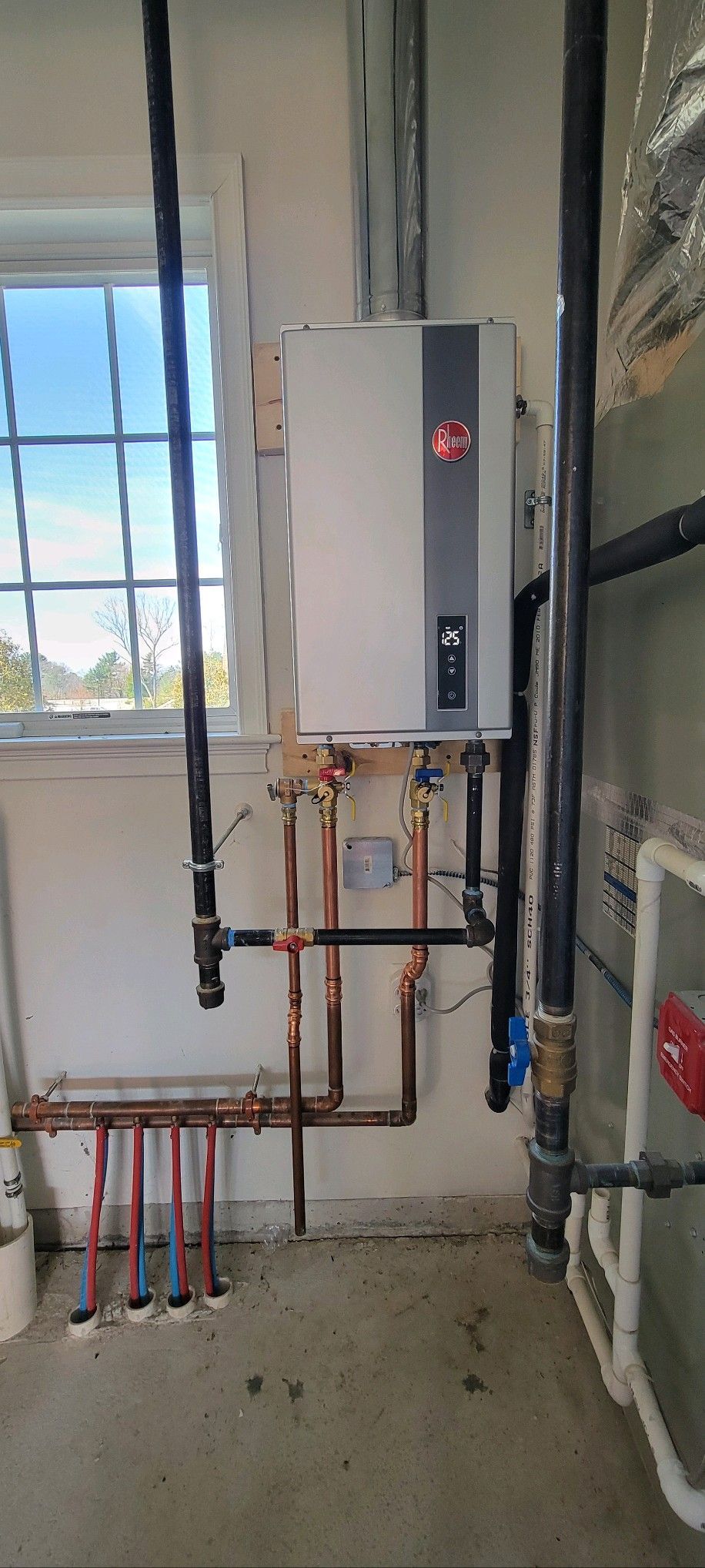 A room with a water heater and pipes on the wall.