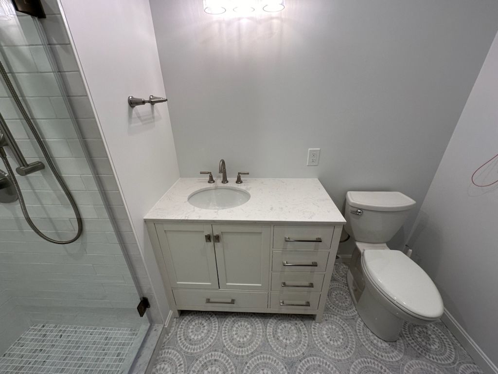 A bathroom with a sink , toilet and shower.