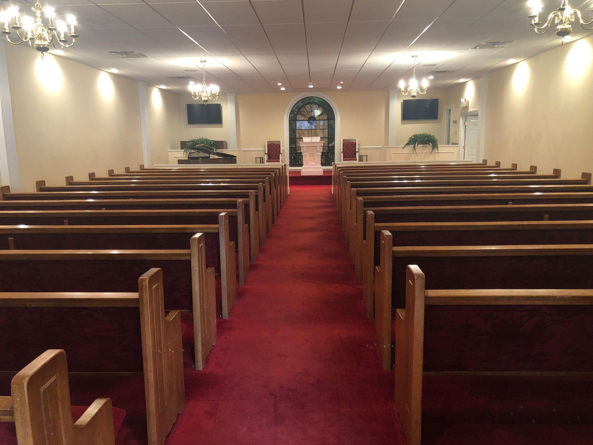 An empty church with red carpet and wooden benches