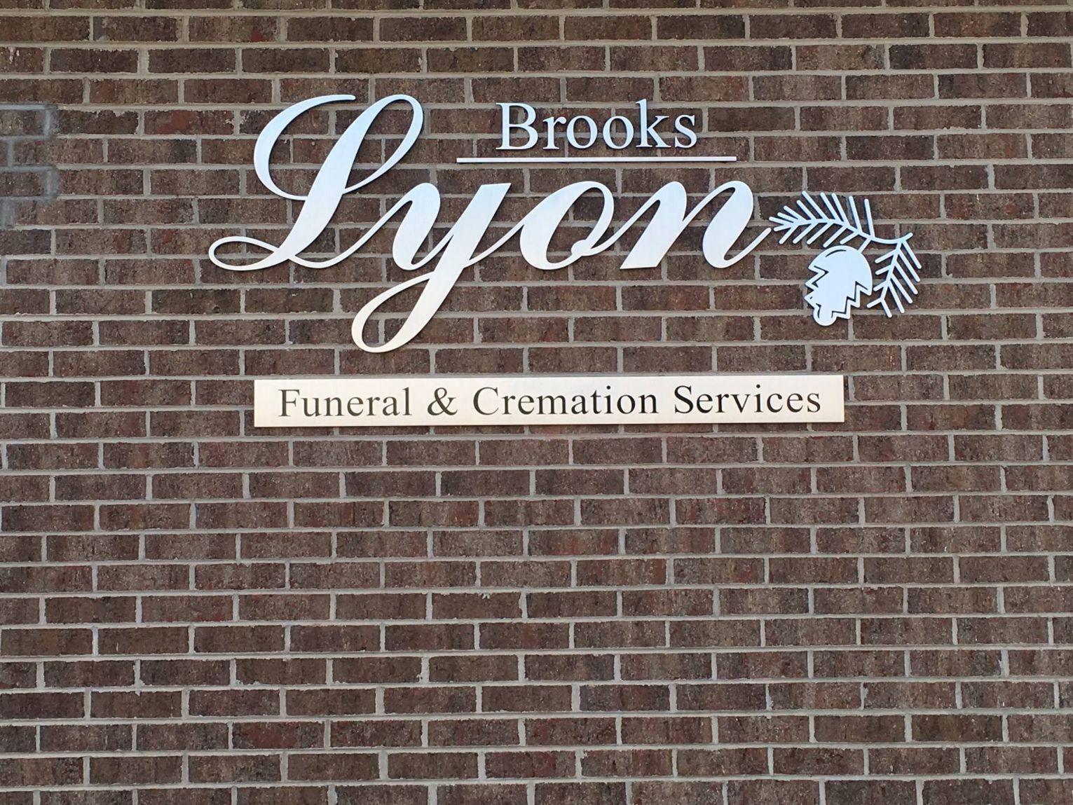 A brick wall with a sign for brooks lyon funeral and cremation services