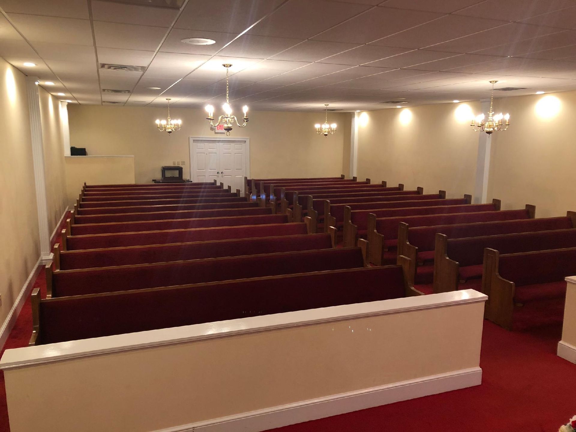 A church with rows of red benches and a red carpet.