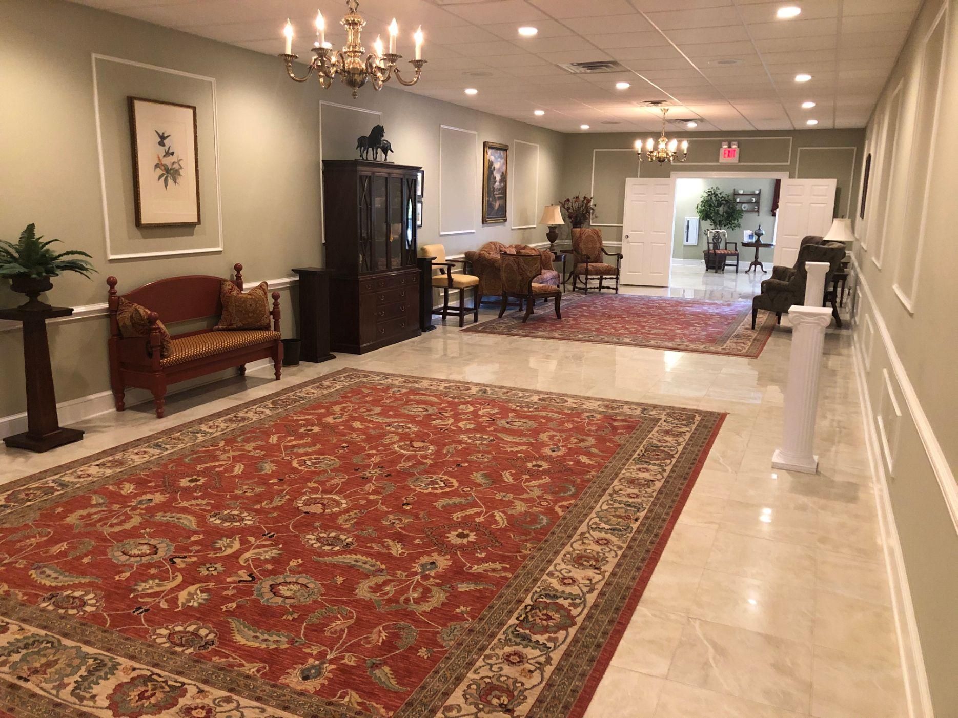 A large hallway with a red rug and a chandelier.