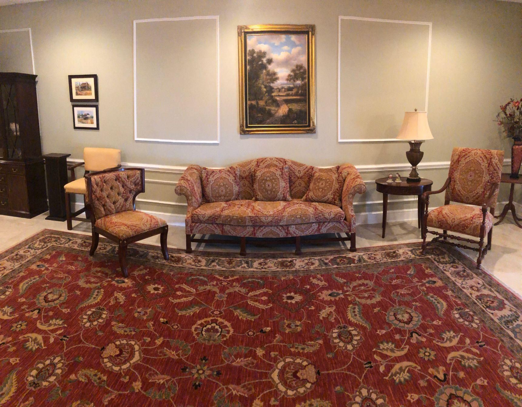 A living room with a couch , chairs and a rug.