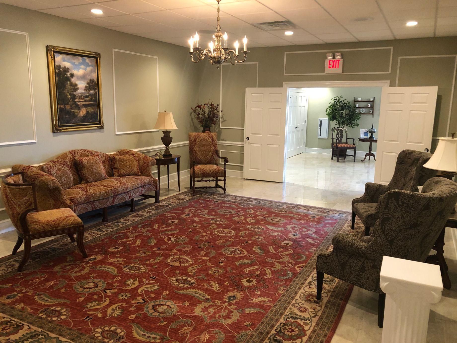 A living room with a couch , chairs , lamps and a rug.