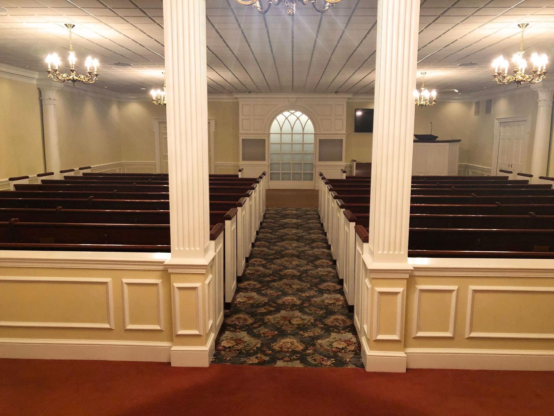 A church with rows of wooden benches and a red carpet