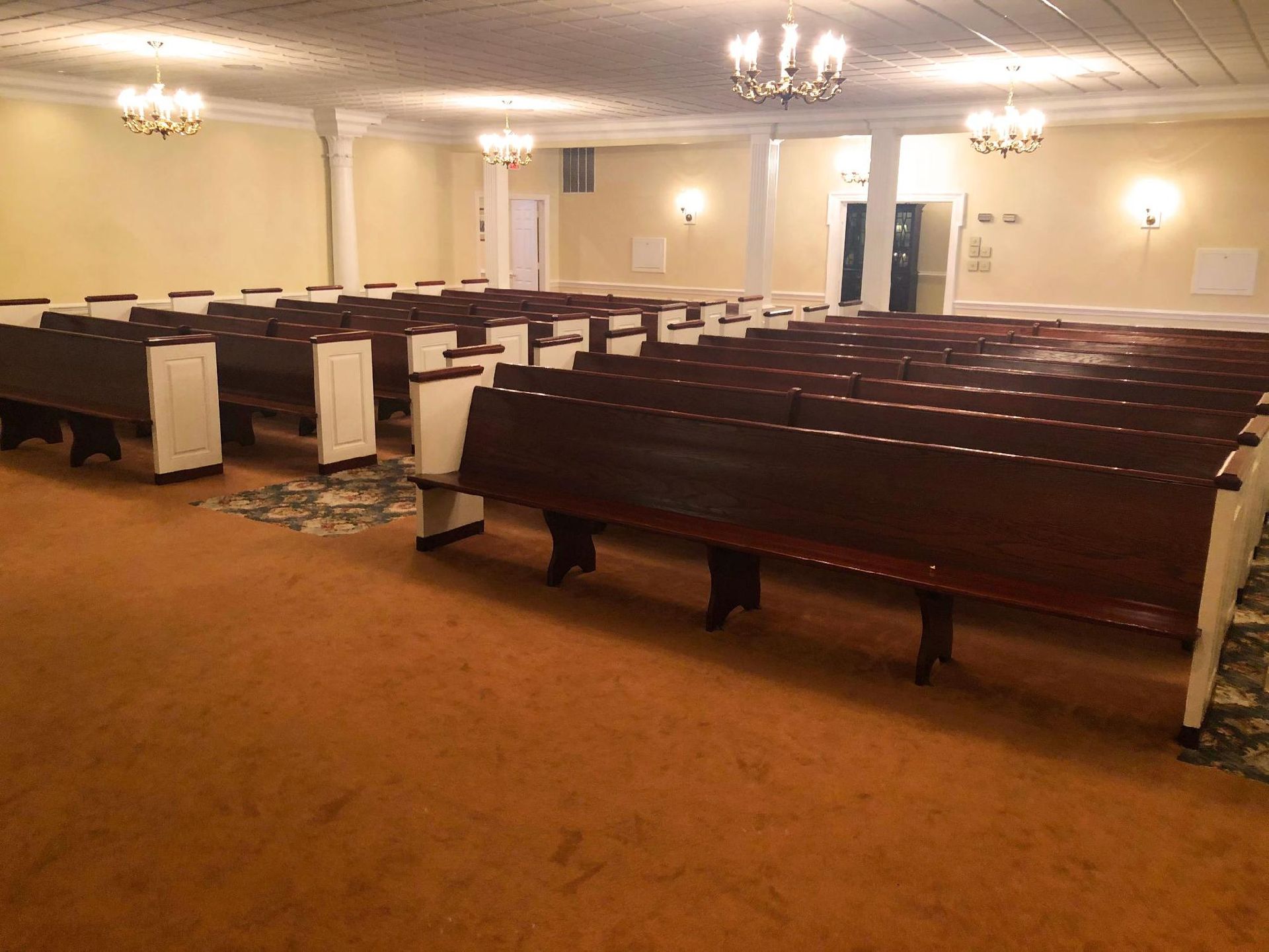 An empty church with rows of wooden benches and a chandelier