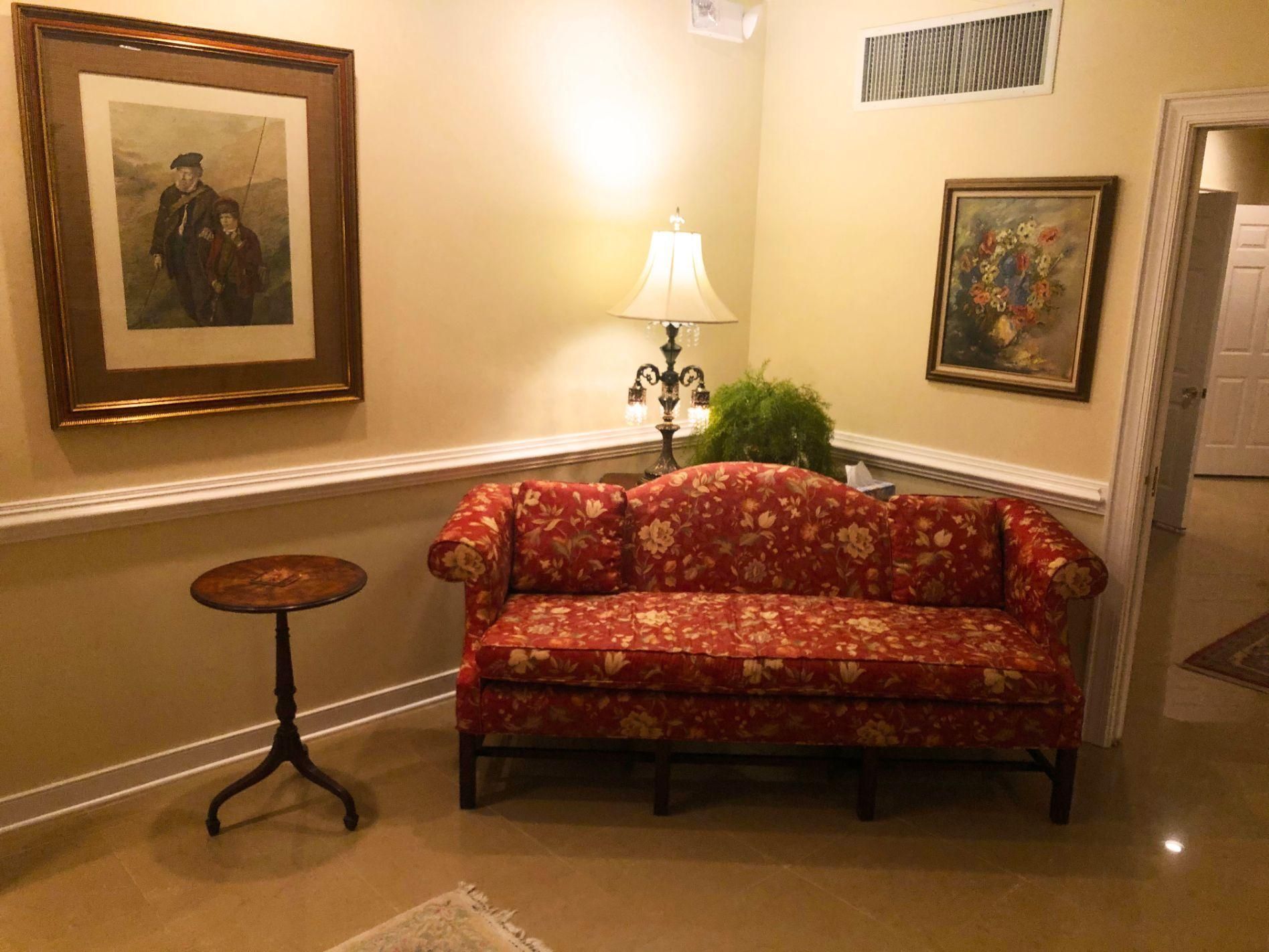 A living room with a red couch and two paintings on the wall
