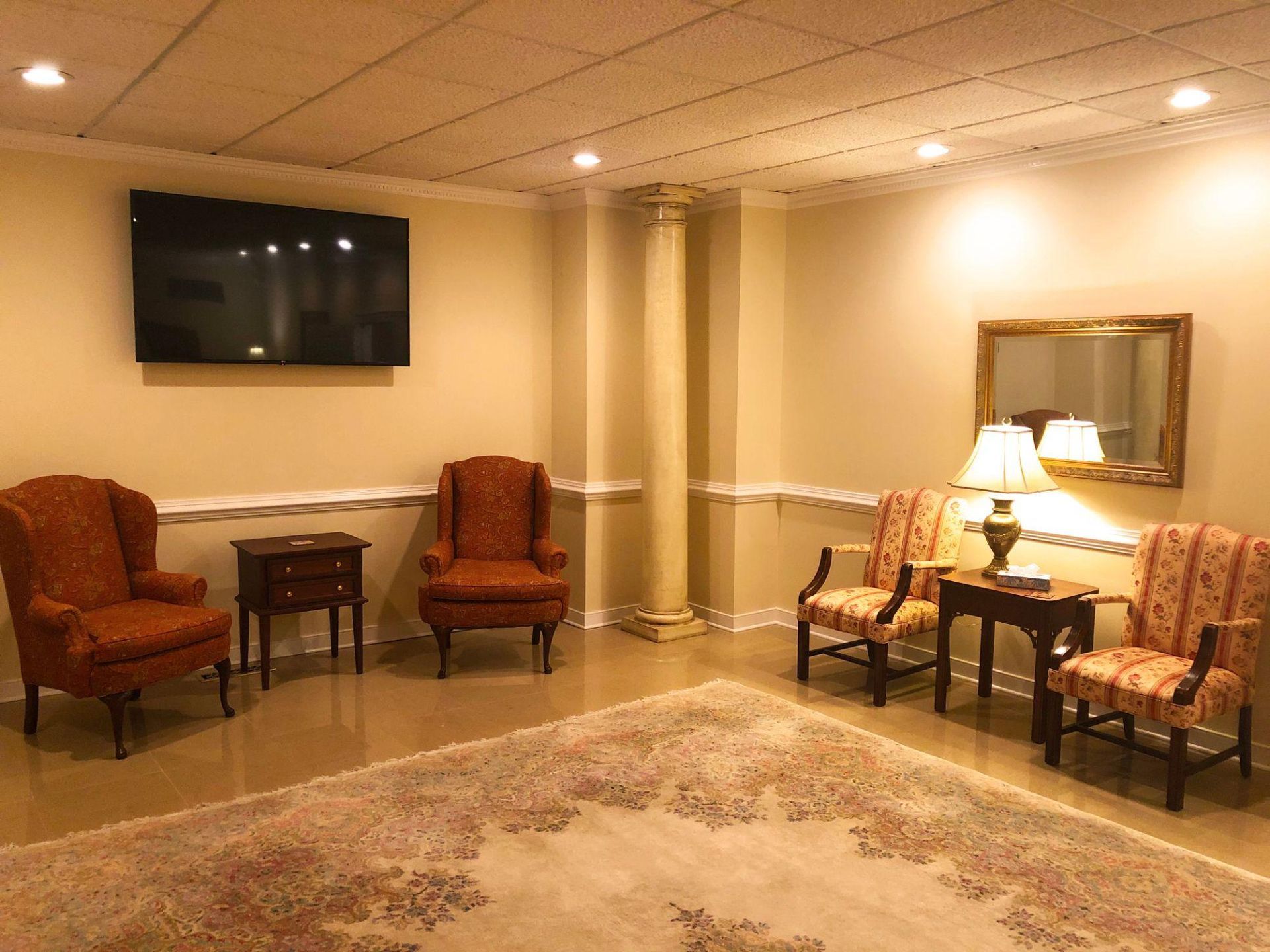 A living room with chairs , tables , lamps and a flat screen tv.