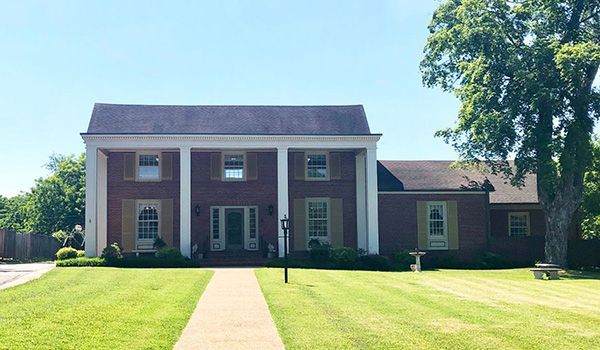 A large brick house with a large lawn in front of it.