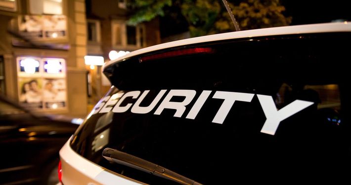 Security decal on a white vehicle window at night, city lights blurred in the background