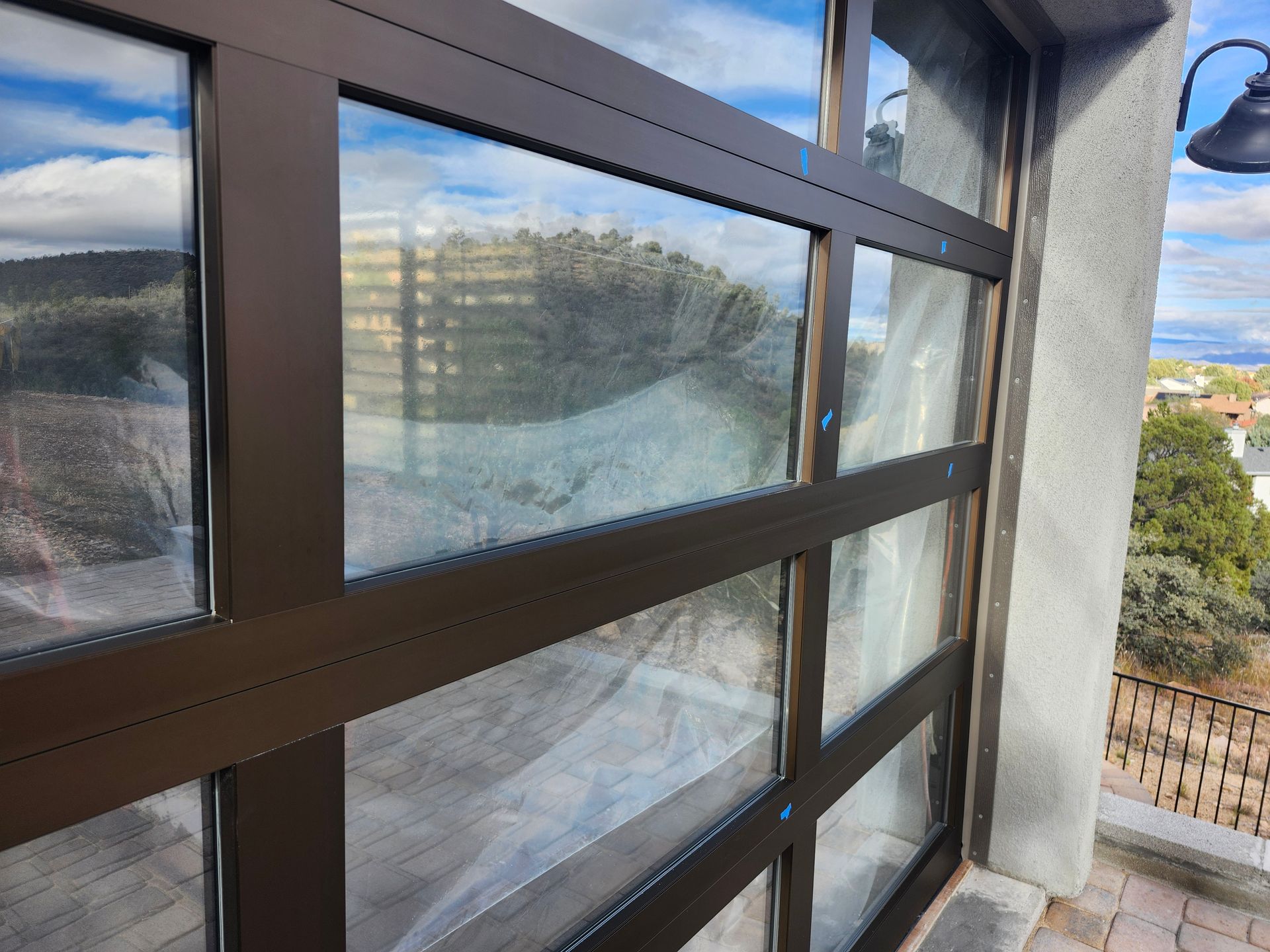 Brown-framed glass door, exterior view. Partially cloudy sky reflected.