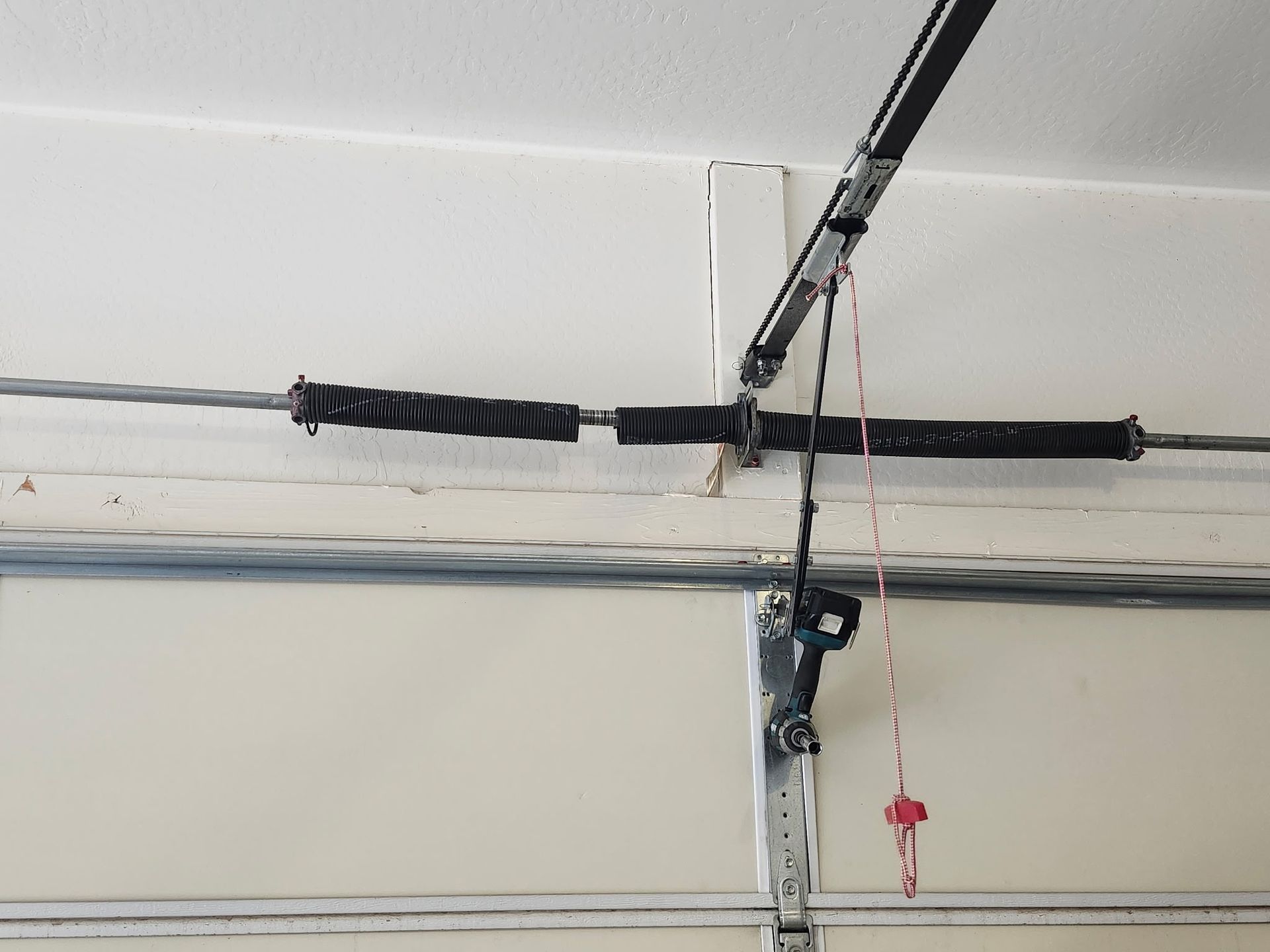 Garage door spring system with two black springs and cables.