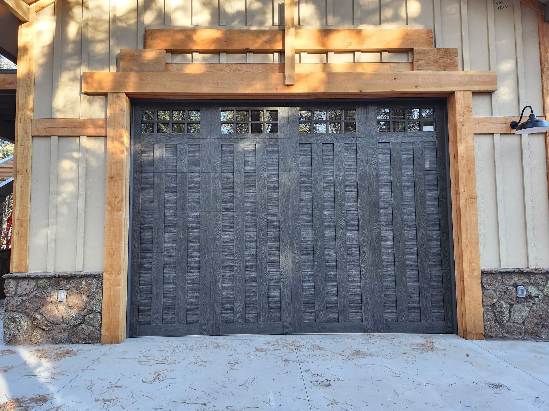 Gray garage door with a textured pattern and wooden trim.