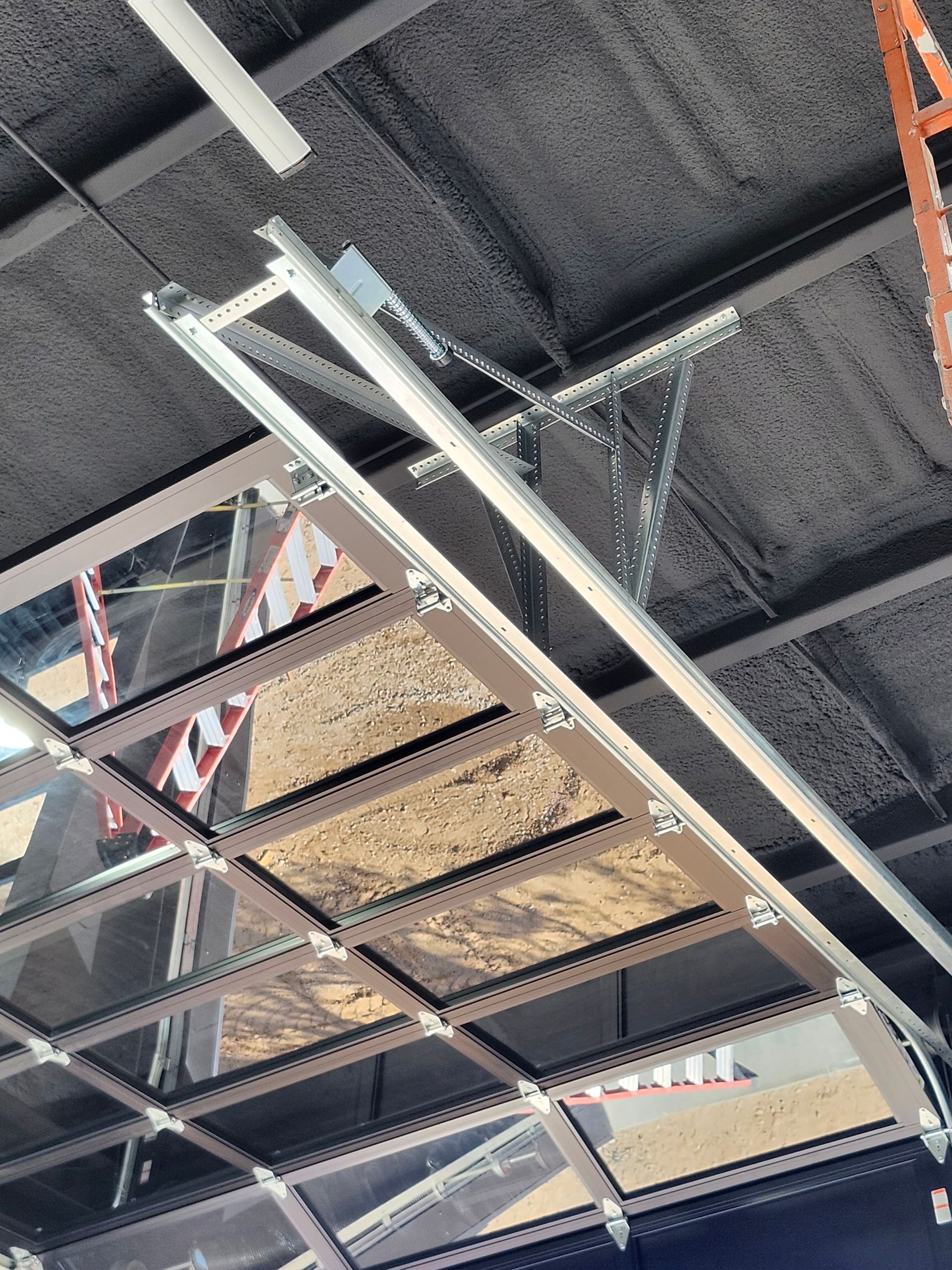 Garage door, steel frame and glass panels, ceiling mounted track, supporting structure visible.