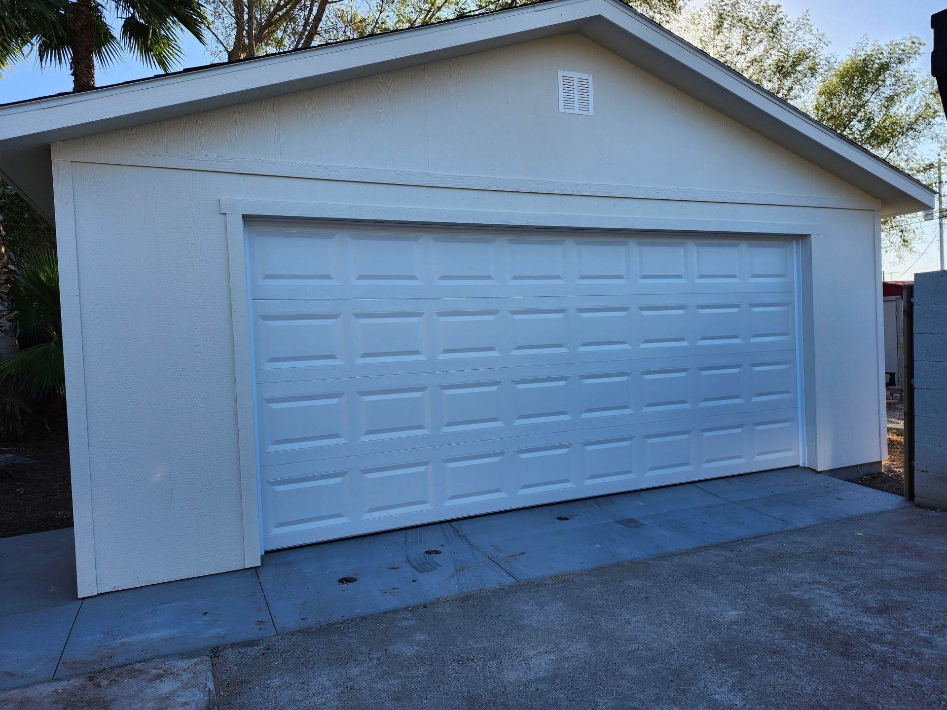 White garage with closed door on concrete slab.