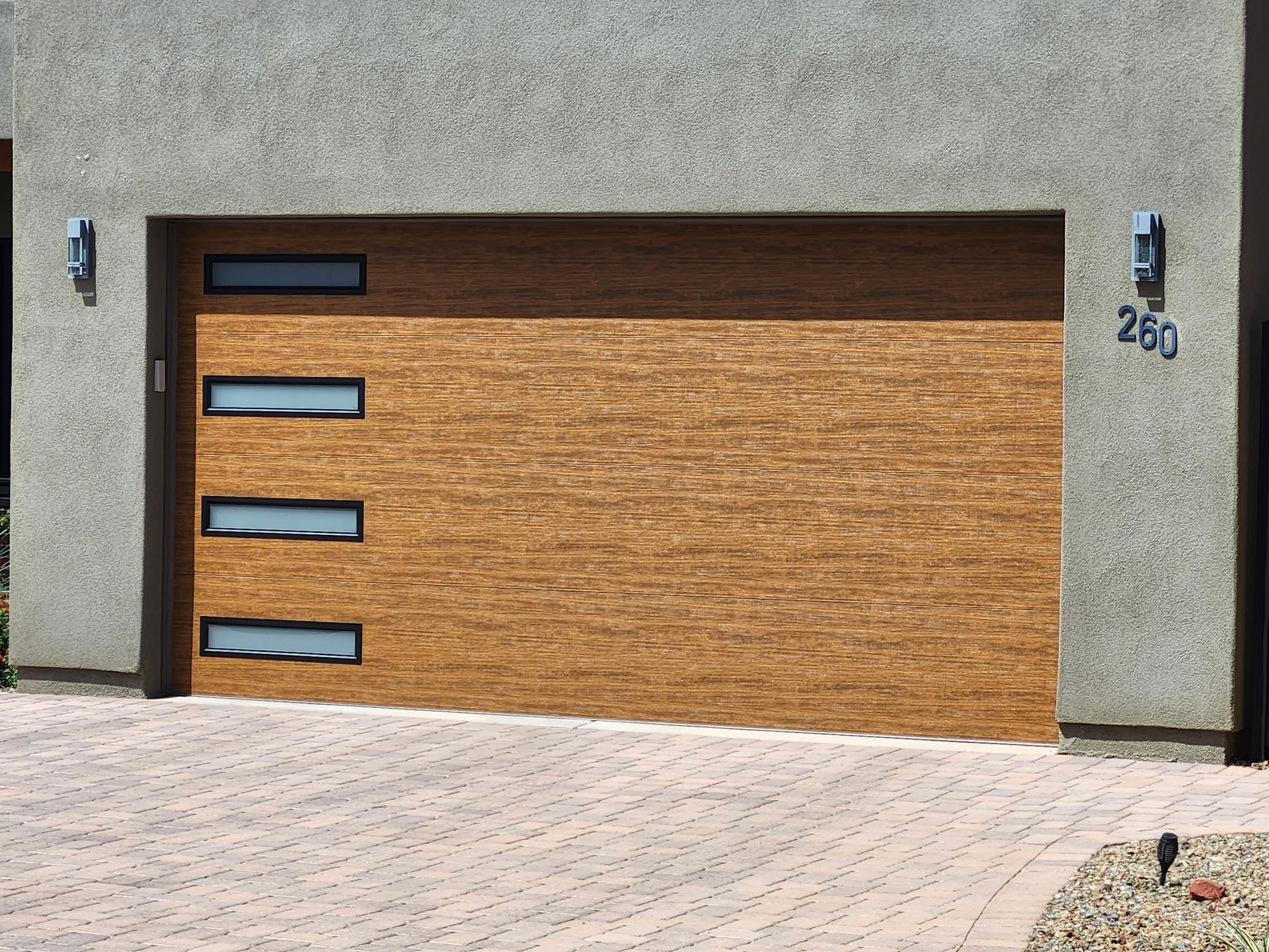 Tan garage door with three horizontal window panels and the number 260.