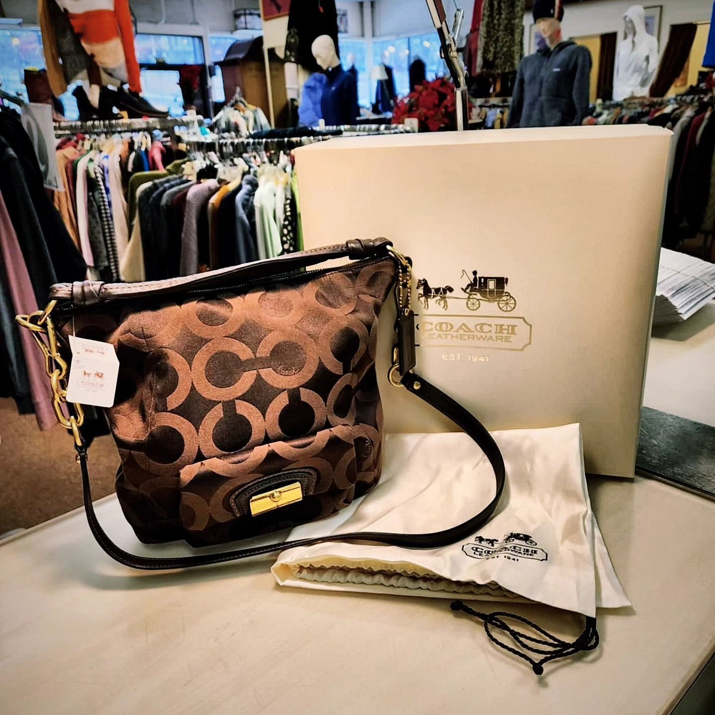 A coach purse sits on a table next to a box