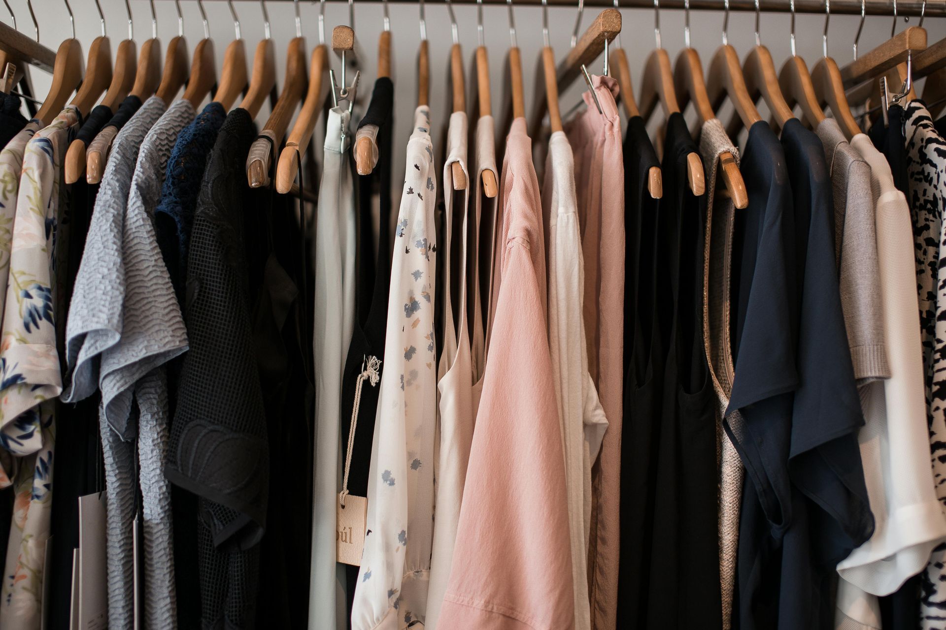 A closet filled with clothes hanging on wooden hangers.