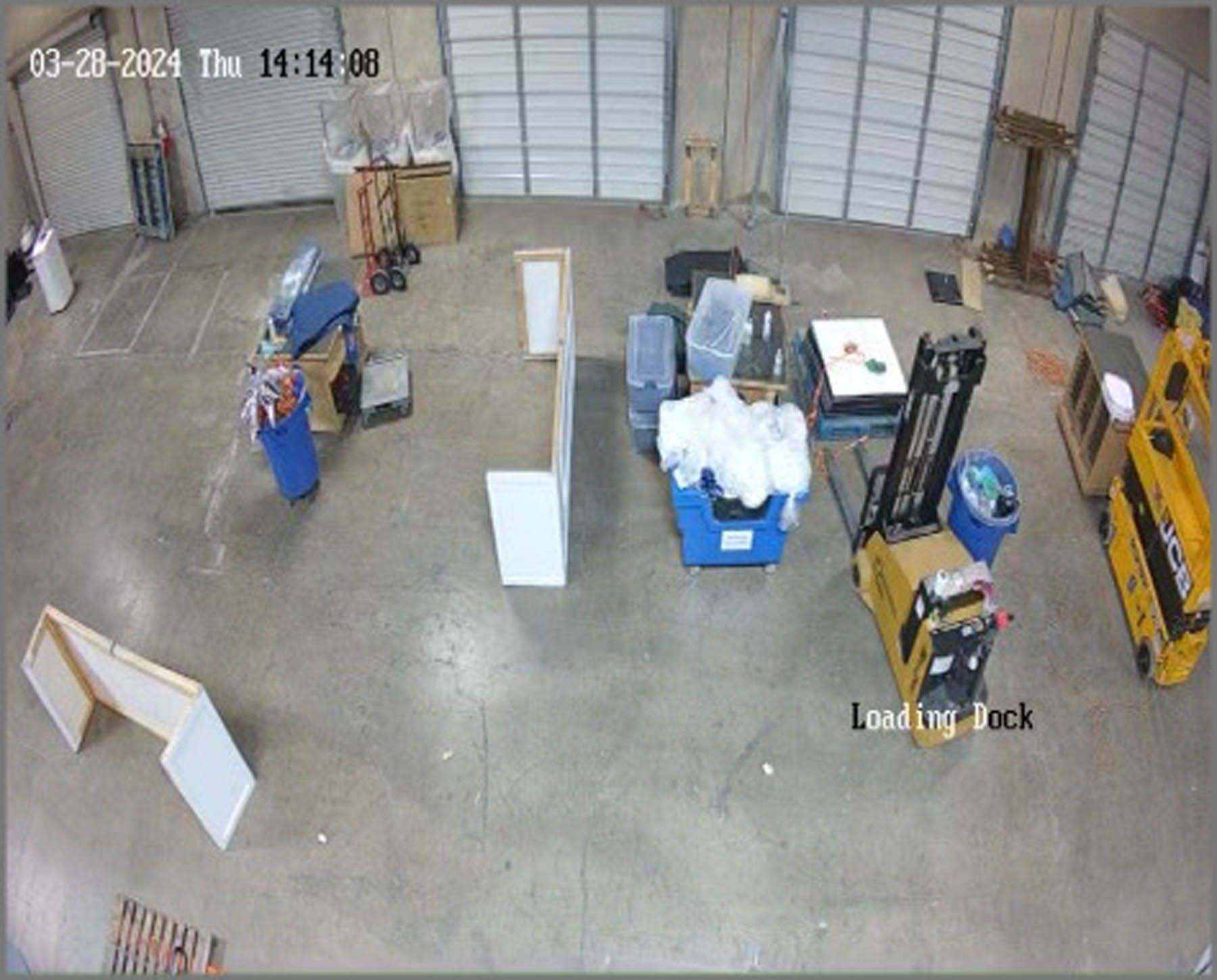 Warehouse interior with a forklift at the loading dock, various objects and materials scattered throughout the space.