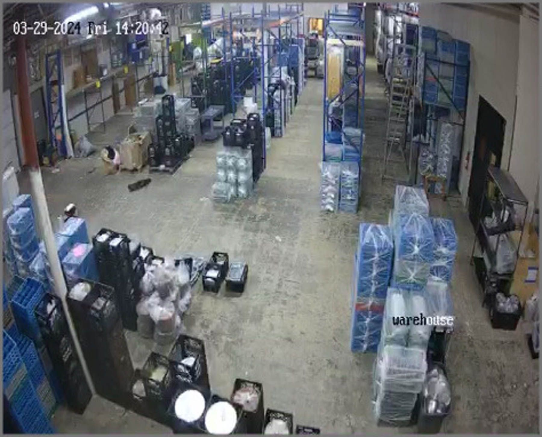 Warehouse interior with stacked goods on shelves and floor. Timestamp visible.