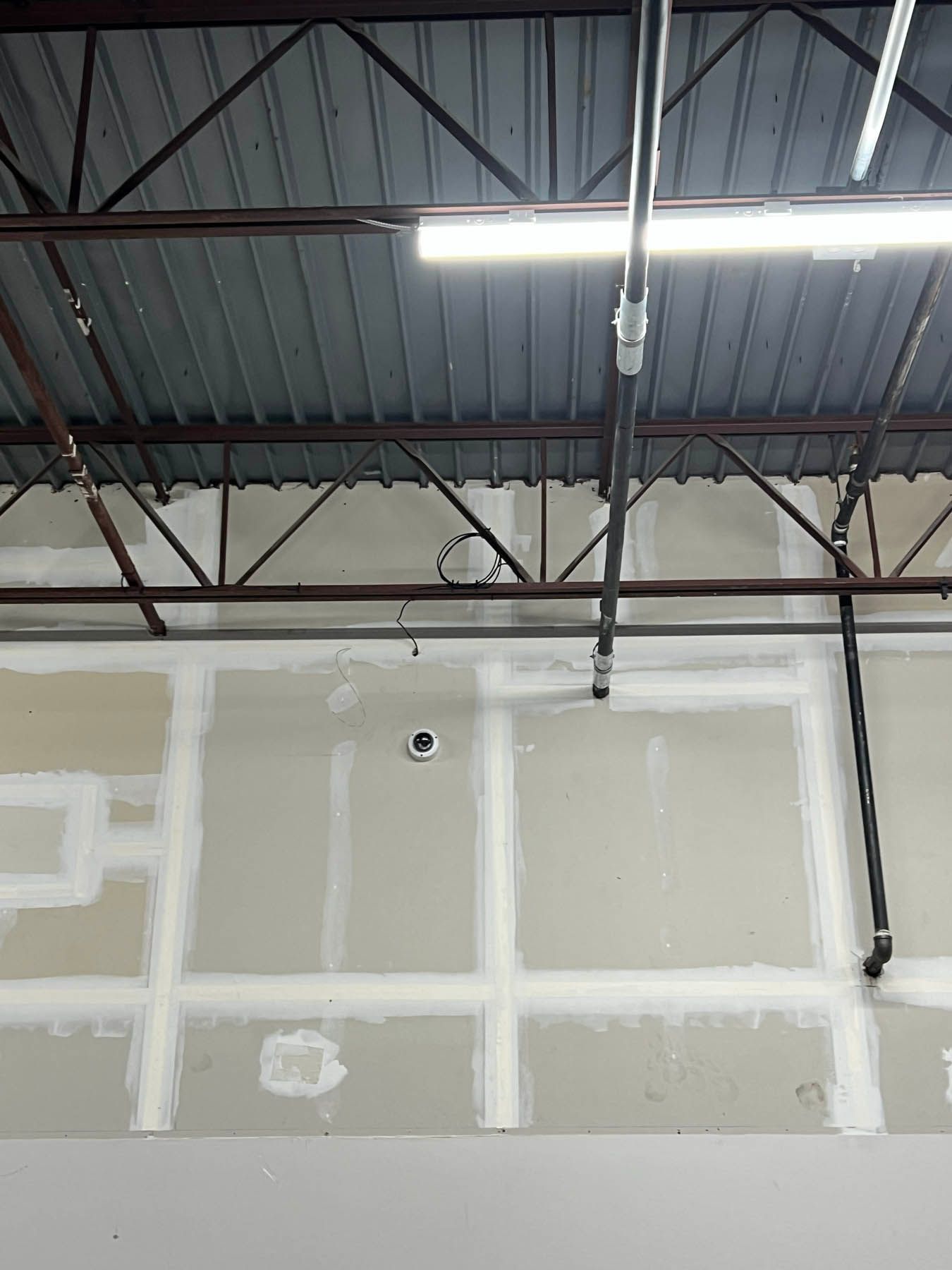 Steel ceiling structure with metal pipes, drywall panels.