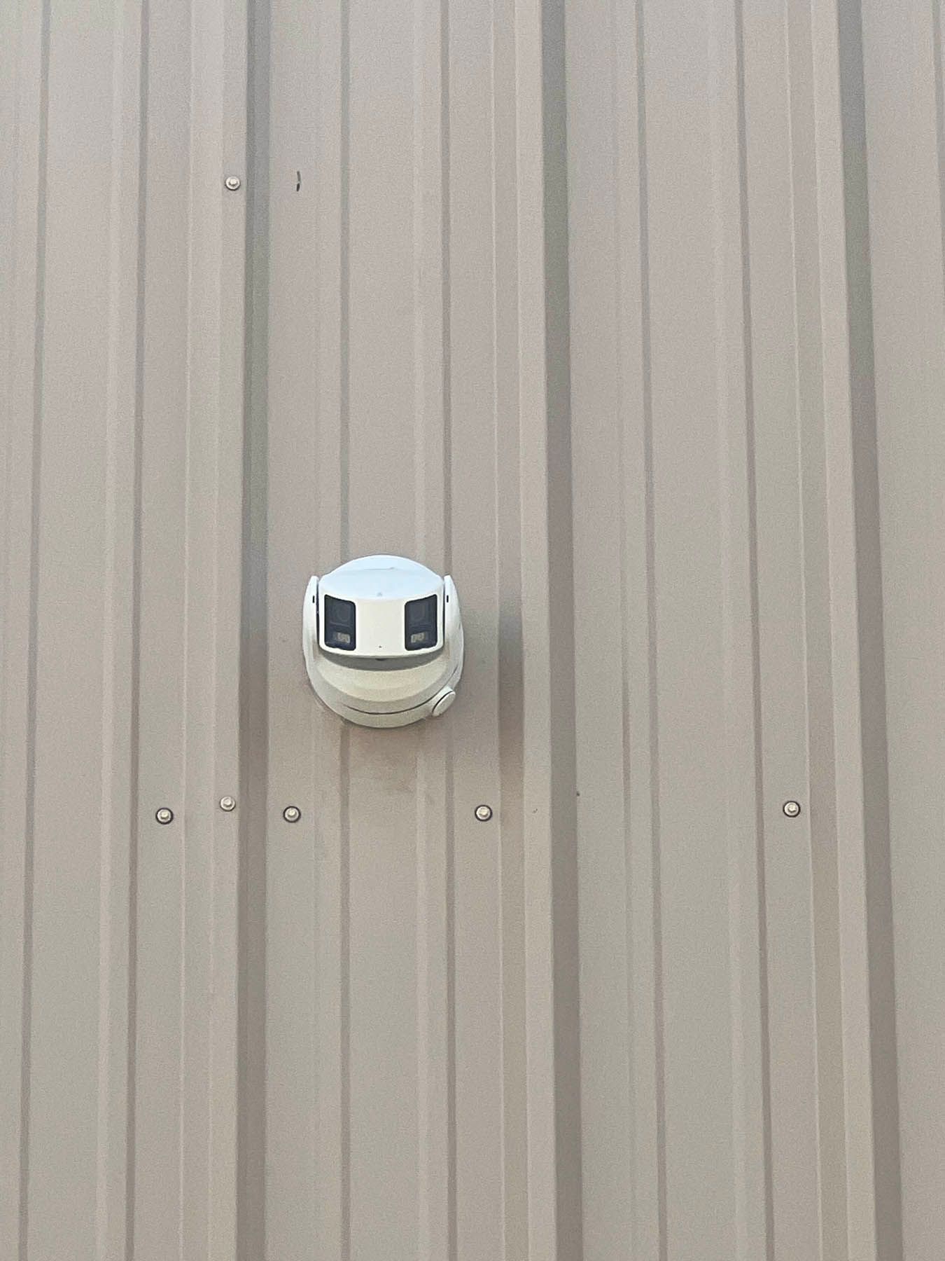 White ventilation cap on a beige corrugated metal wall.
