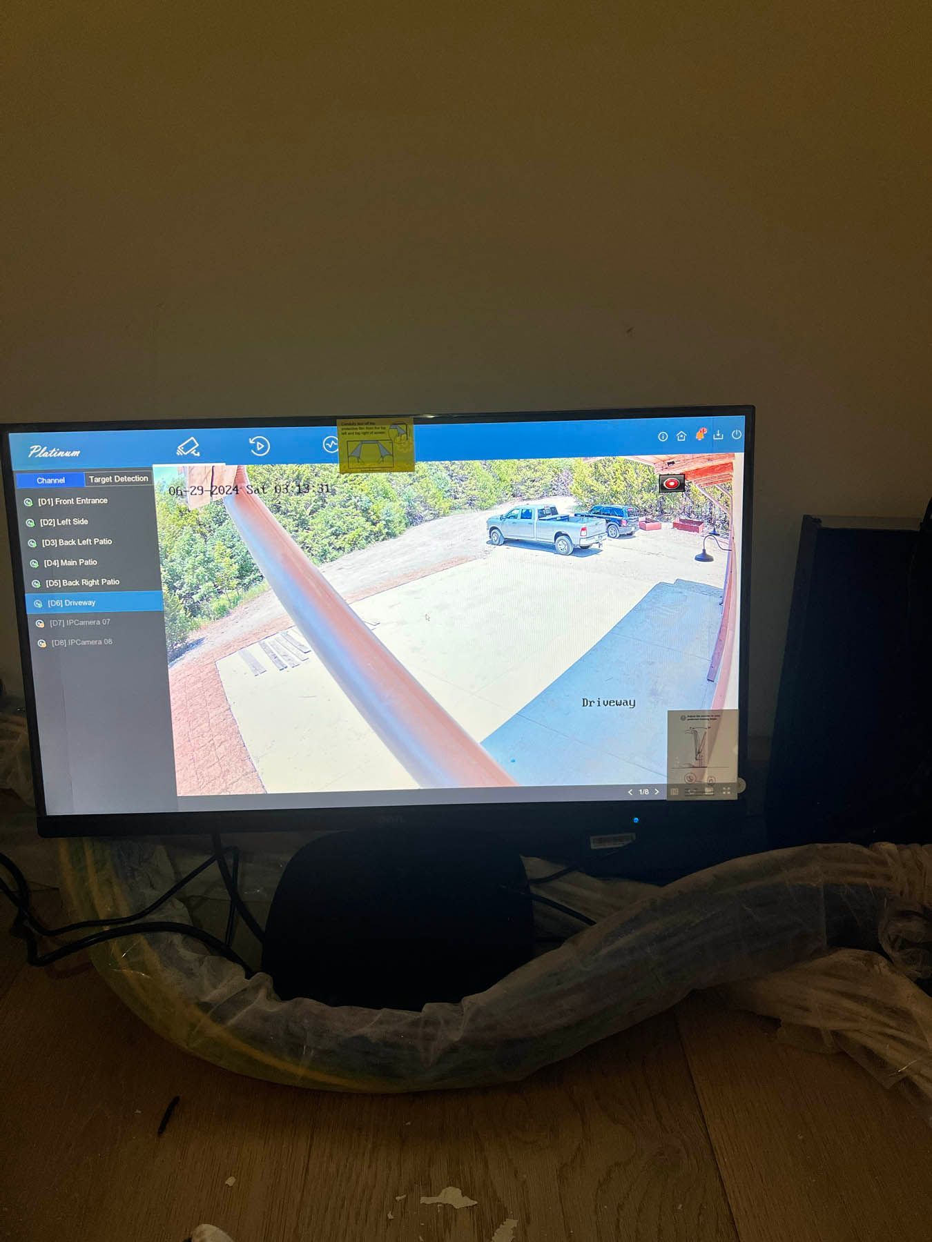 Monitor displaying a security camera feed of a rooftop with a vehicle parked in a driveway.